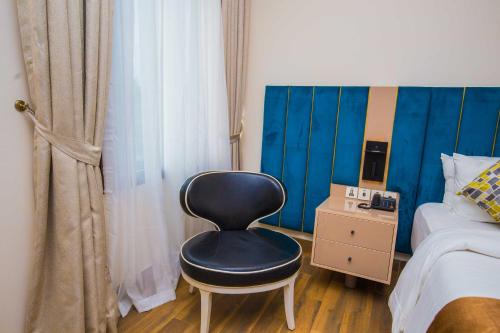 a black chair sitting in a bedroom next to a bed at Qlets Privé in Abuja