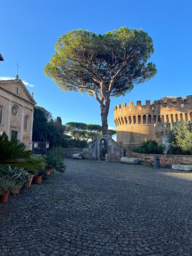 a tree in front of a castle with a stone road at Domus Lido in Lido di Ostia