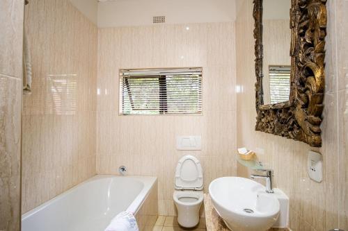 a bathroom with a tub and a toilet and a sink at The Victoria Falls Deluxe Suites in Victoria Falls