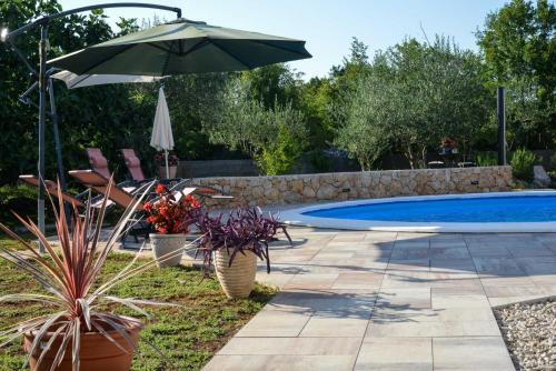 a patio with an umbrella and a swimming pool at Apartment Villa Oliva in Gostinjac