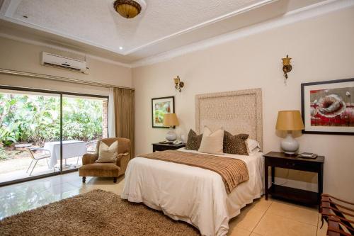 a bedroom with a bed and a chair and a window at The Victoria Falls Deluxe Suites in Victoria Falls