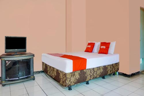 a bedroom with a bed with a tv and a fireplace at SPOT ON 91797 Mutiara Guest House in Karawang