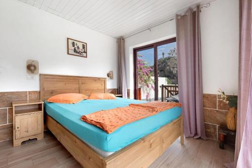 een slaapkamer met een bed met blauwe lakens en een raam bij Nido sobre el barranco piso Bali in Icod de los Vinos