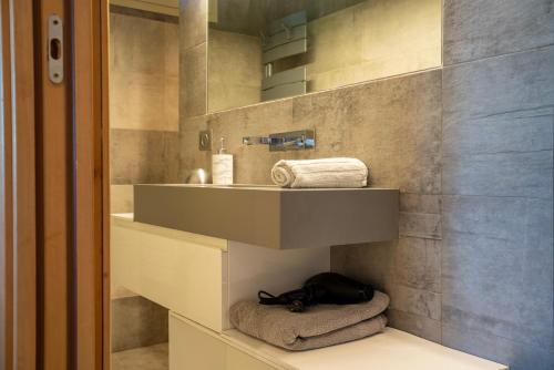 uma casa de banho com um lavatório e uma prateleira com toalhas em Le petit jardin exotique em Beausoleil