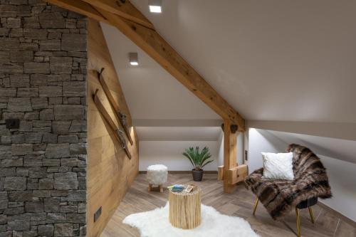 an attic room with a stone wall and a chair at Mairnaige, luxueux appartement avec sauna in Gérardmer