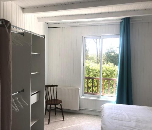 une chambre avec un lit et une fenêtre avec une chaise dans l'établissement Domaine Shanti Lande, à Ménesplet