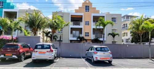 three cars parked in a parking lot in front of a building at La Marquise in Flic-en-Flac