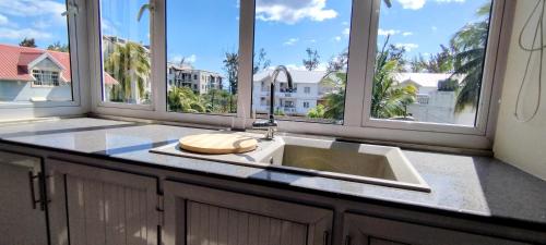 a kitchen with a sink and some windows at La Marquise in Flic-en-Flac