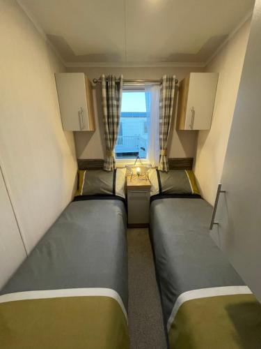 two beds in a small room with a window at PRESTIGE GOLF VILLAGE CARAVAN in Port Seton
