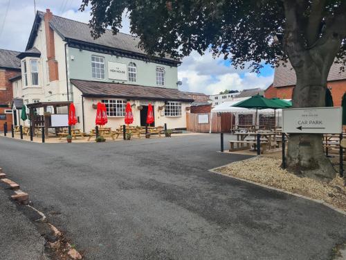 a building with tables and umbrellas next to a street at The Hen House in Cannock