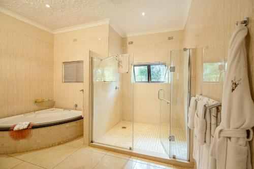 a bathroom with a shower and a bath tub at The Victoria Falls Deluxe Suites in Victoria Falls
