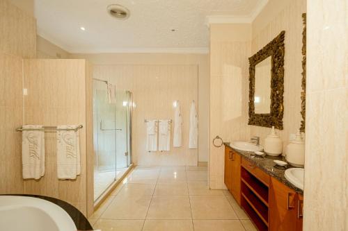 a bathroom with a tub and a sink and a shower at The Victoria Falls Deluxe Suites in Victoria Falls