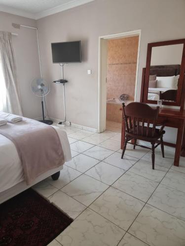 a bedroom with a bed and a chair and a mirror at Palm villa in Harare