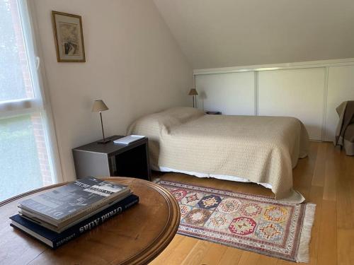 - une chambre avec un lit et une table avec des livres dans l'établissement PETIT AILLY magnifique logement accès plage à pied, à Varengeville-sur-Mer