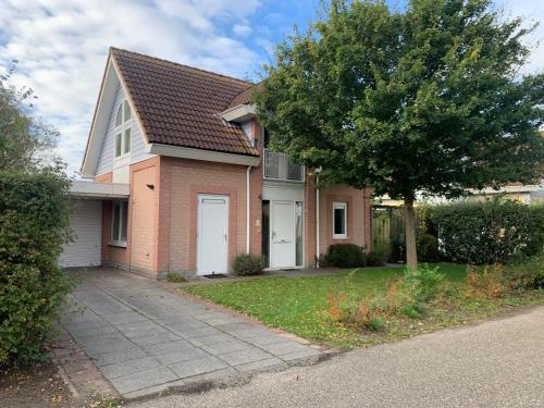 a brick house with a tree and a driveway at Holidayhouse Banjaard in Kamperland
