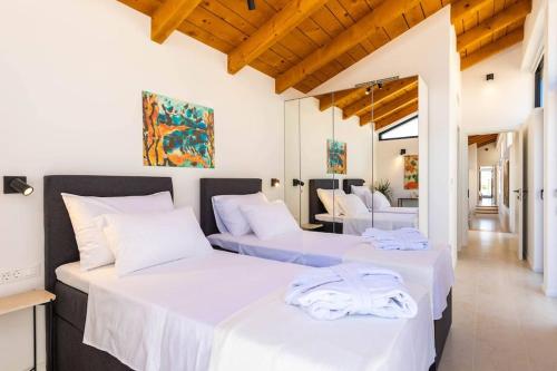 2 letti in una camera con pareti bianche e soffitti in legno di Villa M - Dubrovnik a Zaton