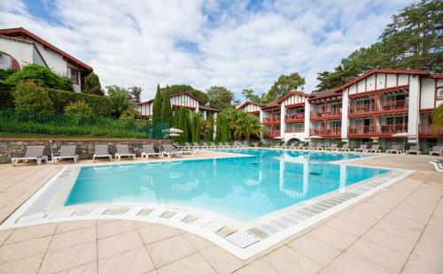einen Pool in einem Resort mit Stühlen und einem Gebäude in der Unterkunft Résidence Pierre & Vacances La Villa Maldagora in Ciboure