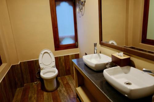 a bathroom with a toilet and a sink and a mirror at Taktsang Village Resort in Paro