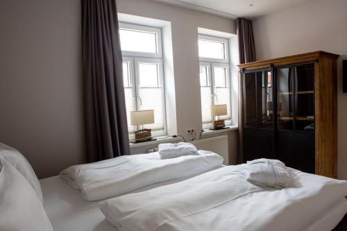 two beds in a room with two windows at Romantik Hotel Aquarium in Friedrichstadt