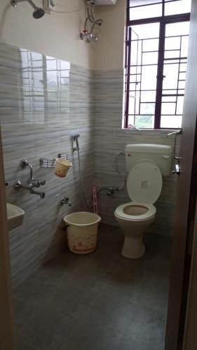 een badkamer met een toilet, een wastafel en een raam bij VERA Inn in Cherrapunji