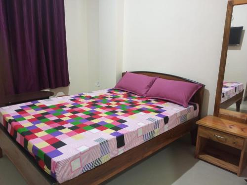 een slaapkamer met een bed met een kleurrijke quilt bij VERA Inn in Cherrapunji