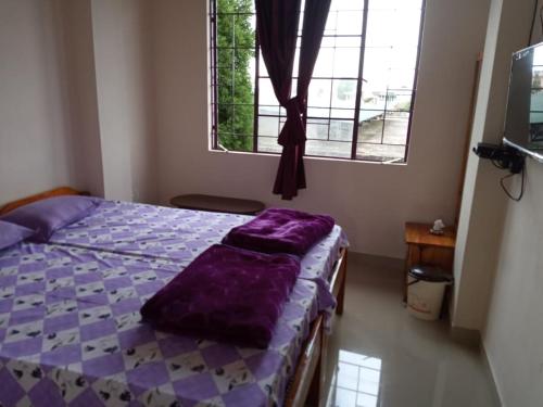 een slaapkamer met een bed met een paars kussen erop bij VERA Inn in Cherrapunji