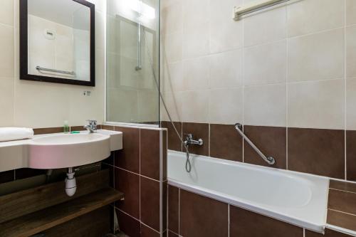 a bathroom with a sink and a bath tub at Résidence Pierre & Vacances Le Clos d'Eguisheim in Eguisheim