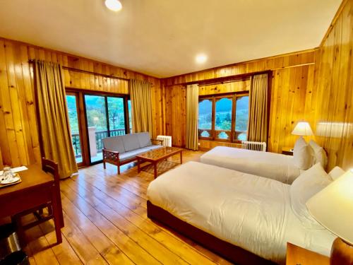 Taktsang Village Resort في بارو: غرفة نوم بسريرين واريكة وطاولة