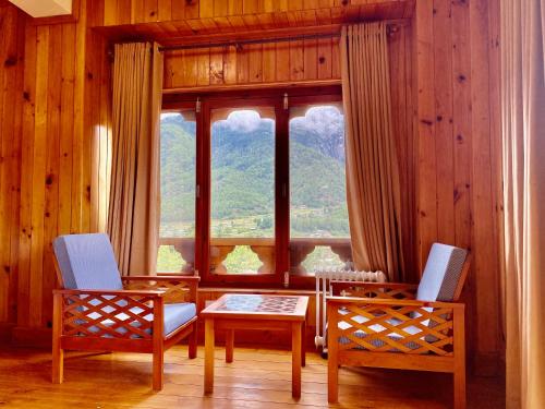 a room with two chairs and a table and a window at Taktsang Village Resort in Paro