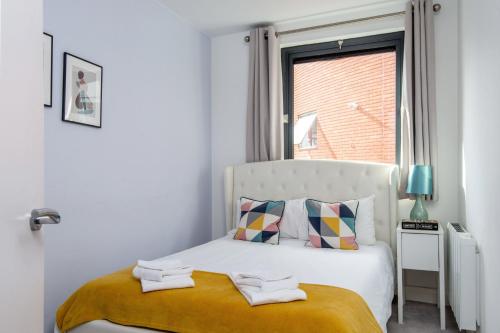 a white bedroom with a bed with a window at Mulberry South Penthouse by City Living London in London