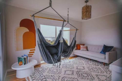 ein Wohnzimmer mit einer Hängematte und einer Couch in der Unterkunft The Hangout KING BEDS Hammock Chairs with a View in Port Campbell