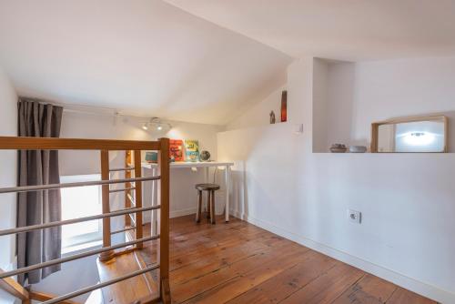 Pokój z białymi ścianami, drewnianymi podłogami i schodami w obiekcie Alfama 2BDR Duplex Apartment W/ Balcony by LovelyStay w Lizbonie