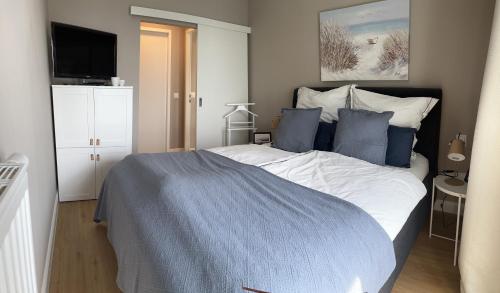 a bedroom with a large bed with blue pillows at Wohnen am Meer in Zingst