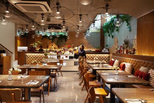 a woman standing in a restaurant with tables and chairs at Volve Hotel Bangkok in Bangkok