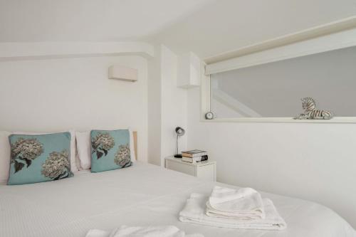 a white bedroom with a bed with blue pillows and a window at Mulberry North Penthouse by City Living London in London