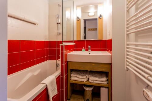 La salle de bains rouge et blanche est pourvue d'un lavabo et d'une baignoire. dans l'établissement Résidence Pierre & Vacances Les Gémeaux, à Belle Plagne