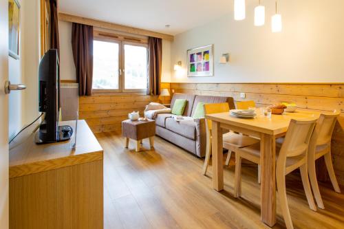 un salon avec un canapé et une table avec une télévision dans l'établissement Résidence Pierre & Vacances Les Gémeaux, à Belle Plagne