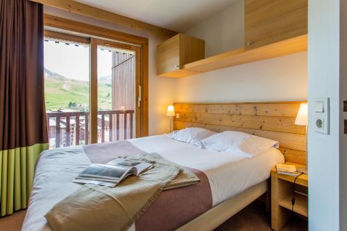 a bedroom with a bed with a book on it at Résidence Pierre & Vacances Les Gémeaux in Belle Plagne