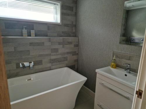 a bathroom with a white tub and a sink at Maple 2 Bedroom Luxury Lodge in Mid Wales in Welshpool