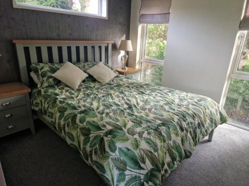 a bedroom with a bed with a green blanket and pillows at Maple 2 Bedroom Luxury Lodge in Mid Wales in Welshpool