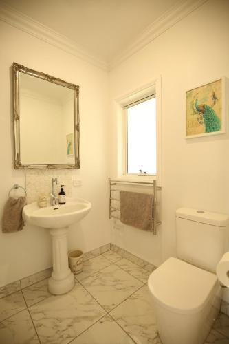 Baño blanco con aseo y lavamanos en Bridgecroft Villa - French Provincial in Richmond with spa, en Richmond