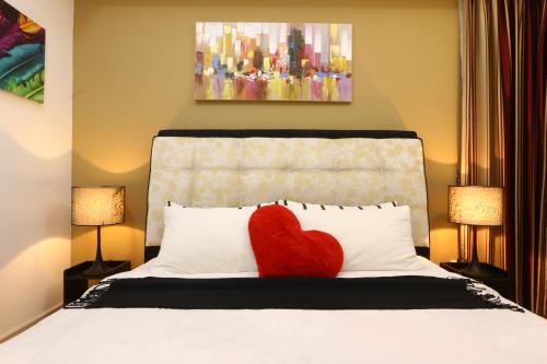 a red heart pillow on a bed with two lamps at Suasana Bukit Ceylon Residence in Kuala Lumpur