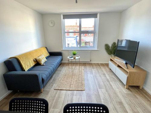a living room with a blue couch and a flat screen tv at Central, Bright & Spacious Apartment - Parking Included in Bournemouth