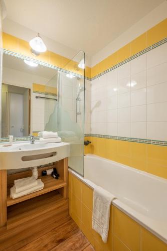 une salle de bain avec un lavabo, une baignoire et un miroir dans l'établissement Résidence Pierre & Vacances Les Sentiers du Tueda, à Méribel