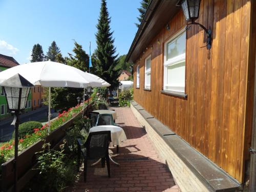 un patio avec des tables et un parasol à côté d'un bâtiment dans l'établissement Pension Haus Ruth - Gartenhaus, à Stadt Wehlen