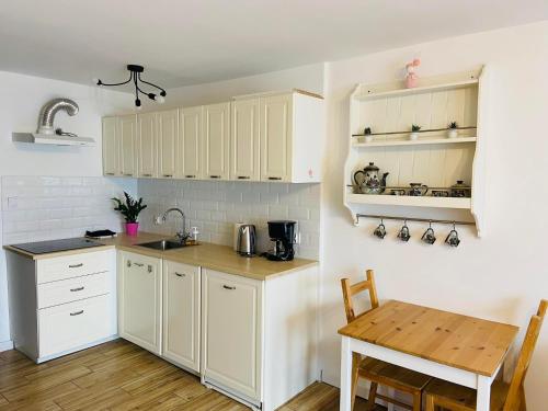 une cuisine avec des placards blancs et une table en bois dans l'établissement Apartament przy Zdrojowej, à Ciechocinek