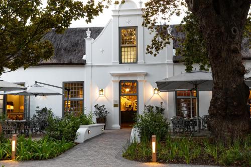 a white building with tables and umbrellas at Erinvale Estate Hotel & Spa in Somerset West