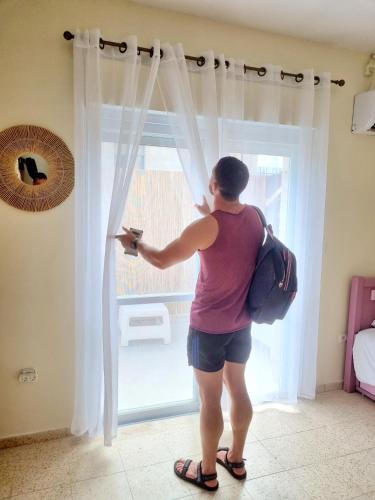 a woman is opening a window in a room at Mike's House Jerusalem in Jerusalem