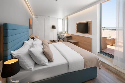 a bedroom with a bed and a desk and a television at Valamar Meteor Hotel in Makarska
