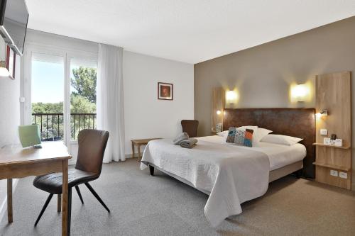 a hotel room with a bed and a desk and a window at Hotel Restaurant Logis Le Tropicana in Douville